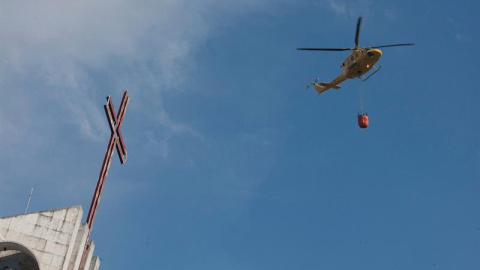 Un helicóptero que transporta agua se acerca hasta las inmediaciones del almacén pirotécnico/EFE