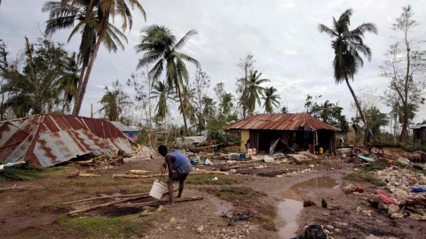 Un hombre recoge agua de una zona destrozada por el huracán Matthew, en Cavaillon, Haití. - REUTERS