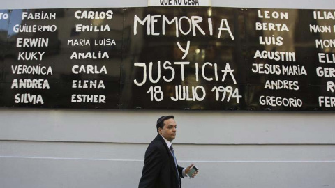 Un hombre camina bajo un cartel durante una manifestación para exigir justicia tras la muerte del fiscal argentino Alberto Nisman en el exterior de la sede de la AMIA en Buenos Aires. - EFE