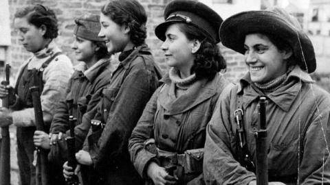 Un grupo de jóvenes mujeres forman sosteniendo unos fusiles.- MUJERES EN GUERRA