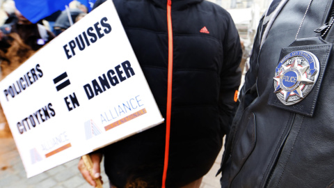 Dos agentes de la Policía francesa, en la manifestación ante el Ministerio de Justicia, en París, uno de ellos sujeta una pancarta que, en francés, dice: "Policías exhaustos0 ciudadanos en peligro". REUTERS / Jacky Naegelen