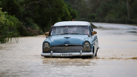 Un coche circula por una carretera inundada de Guantánamo tras el paso del huracán Matthew. / ALEXANDRE MENEGHINI (REUTERS)