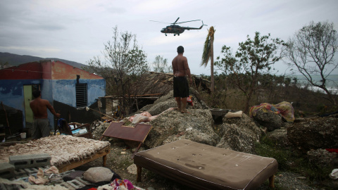 Un hombre observa un helicóptero en Cajobabo (Cuba) tras el paso del huracán Matthew. / ALEXANDRE MENEGHINI (REUTERS)