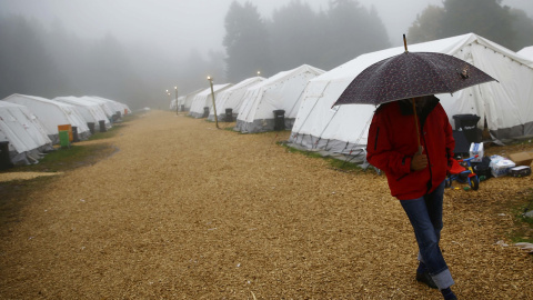 Un refugiado camina bajjo la lluvia en el campamento temporal de Schwarzenborn (Alemania). REUTERS/Kai Pfaffenbach