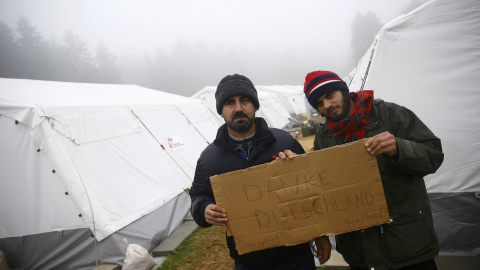 Dos refugiados  del campamento temporal de Schwarzenborn (Alemania) sostienen una cartón en el que han escrito, en alemán, "Gracias Alemania". REUTERS/Kai Pfaffenbach