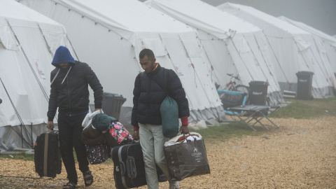 Dos refugiados trasladan sus pertenencias al abandonar un refugio temporal con temperaturas que rozan los cero grados cerca de Schwarzenborn (Alemania). EFE/Boris Roessler