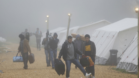 Varios refugiados con sus pertenencias se dirigen a los autobuses que los trasladarán a sus albergues de residencia definitivos, desde el refugio temporal de Schwarzenborn (Alemania). REUTERS/Kai Pfaffenbach