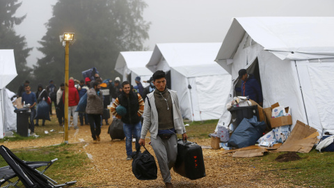 Varios refugiados con sus pertenencias se dirigen a los autobuses que los trasladarán a sus albergues de residencia definitivos, desde el refugio temporal de Schwarzenborn (Alemania). REUTERS/Kai Pfaffenbach