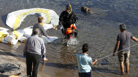 Un guardacostas griego saca del agua el cadáver de un niño refugiado en la costa griega de Lesbos. REUTERS/GIORGOS MOUTAFIS