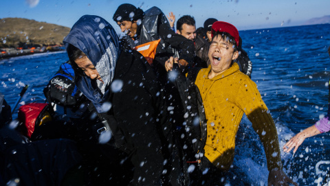 Refugiados y migrantes reaccionan al llegar en un bote a la isla griega de Lesbos, después de cruzar el mar Egeo desde Turquía, el 15 de octubre de 2015. AFP/DIMITAR DILKOFF