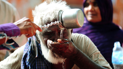 Un hombre bebe agua de una fuente comunal contruida por los vecinos de Allahabad, en India. AFP