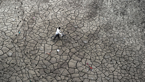 Un pescador indio empuja su bici por el barro seco a las orillas del río Yamuna, en Allahabad, India.  SANJAY KANOJIA (AFP)