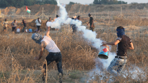 Manifestantes palestinos lanzan piedras contra la valla israelí en Gaza.-REUTERS