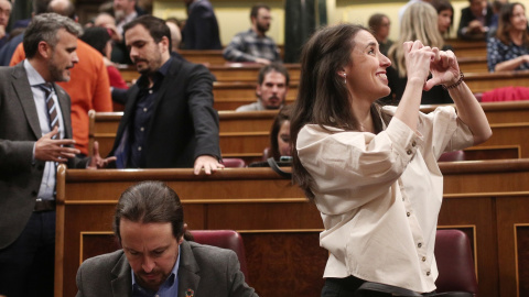 La portavoz de Unidas Podemos en el Congreso, Irene Montero, hace el signo de un corazón con las manos hacia alguien en la tribuna de invitados, junto al secretario general de Podemos, Pablo Iglesias, momentos antes de empezar la segunda se