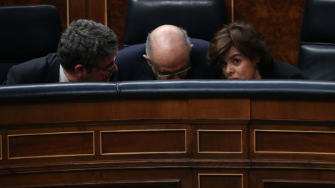 La vicepresidenta del Gobierno, Soraya Sáenz de Santamaría, conversa con los ministros de Energía y de Hacienda, Álvaro Nadal y Cristóbal Montoro, respectivamente, durante el pleno de la moción de censura contra Mariano Rajoy. REUTERS/Susan