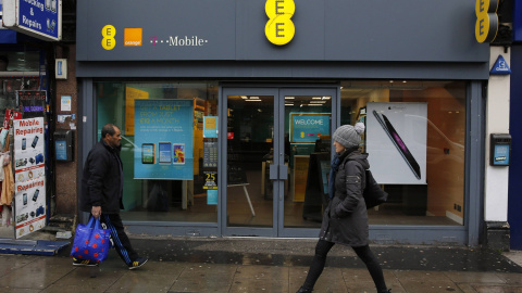 Unos peatones pasan por delante de una tienda de la operadora de telefonía móvil EE en Londres. REUTERS/Suzanne Plunkett