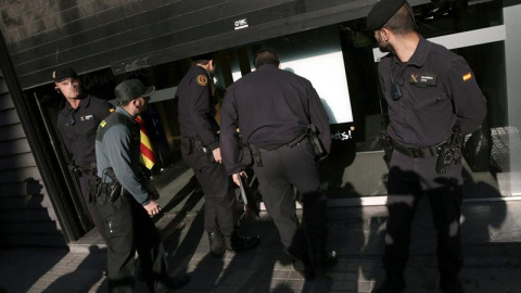 Agentes ante la fachada de la sede de CDC en Barcelona registrada./ EFE