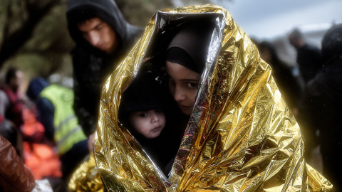 Los niños intentan entrar en calor con mantas de emergencia mientras llegan otros refugiados e inmigrantes a la isla griega de Lesbos. AFP / ARIS MESSINIS