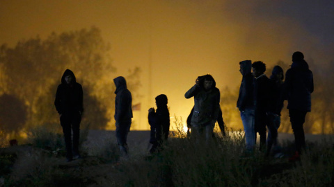 Varias inmigrantes en La Jungla de Calais, con gases lacrimógenos a sus espaldas. REUTERS/Pascal Rossignol