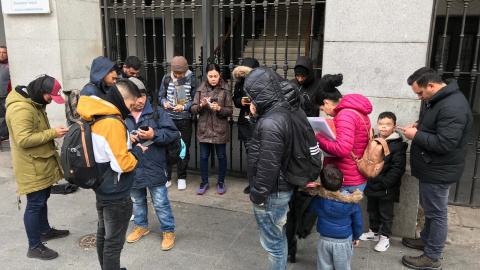 Varios solicitantes de asilo intentan reservar su cita previa de extranjería para acceder al sistema de acogida, en la puerta del Samur Social de Madrid.- RSP