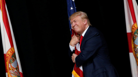 El candidato republicano a la presidencia de Estados Unidos, Donald Trump, abraza una bandera nacional durante un mítin en Tampa, Florida. REUTERS/Jonathan Ernst