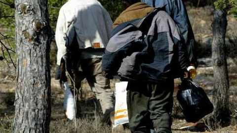 Tres inmigrantes se desplazan por las laderas del monte Gurugú. EFE