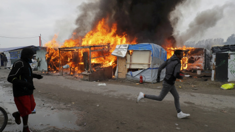 Varios inmigrantes se alejan del incendio en una de las tiendas de la Jungla. - REUTERS