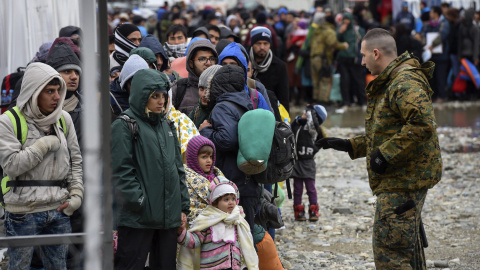 Un agente de policía macedonio conversa con un grupo de refugiados antes de que éstos puedan subir a un tren que se dirige hacia a la frontera serbia, cerca de la ciudad de Gevgelija, Macedonia. EFE