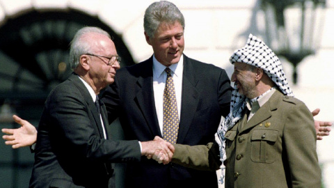 El presidente de EEUU, Bill Clinton, observa mientras el primer ministro israelí Isaac Rabin y el líder de la Organización de Liberación de Palestina (OLP),  Yasser Arafat, se dan la mano después de la firma de del acuerdo de paz en la Casa