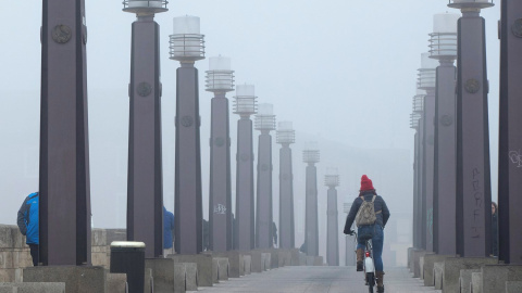 13/01/2020.- Una joven atraviesa en bicicleta el Puente de Piedra sobre el río Ebro a su paso por Zaragoza este lunes. / EFE - JAVIER CEBOLLADA