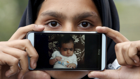 Rubina, llegada a Europa desde Kabul, Afganistán, muestra una foto de su sobrino Iman mientras espera para cruzar la frontera entre Eslovenia y Austria en Sentilj, Eslovenia.- REUTERS / Srdjan Zivulovic