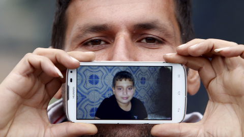 Said, de Teherán, Irán, muestra una foto de su hijo Hossein mientras espera para cruzar la frontera entre Eslovenia y Austria en Sentilj .-REUTERS / Srdjan Zivulovic