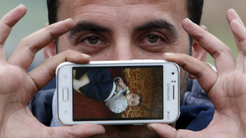 Sirad vivía en Zabadani, Siria. En su móvil guarda una foto de su hijo Jad, que observa mientras espera para cruzar la frontera entre Eslovenia y Austria en Sentilj, Eslovenia.- REUTERS / Srdjan Zivulovic