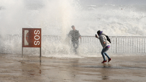 20/01/20- Turistas toman fotos mientras las olas del mar los cubren durante el temporal Gloria en la playa de la Barceloneta, en Barcelona. REUTERS / Nacho Doce