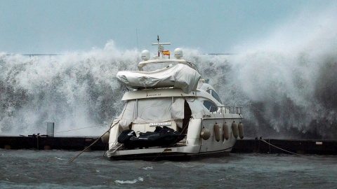 21/01/2020.- Grandes olas sobrepasan el espigón del Puerto Olímpico de Barcelona hundiendo uno de los barcos atracados, este martes en el que Protección Civil ha recomendado evitar los desplazamientos por carretera, sobre todo en el Gironès