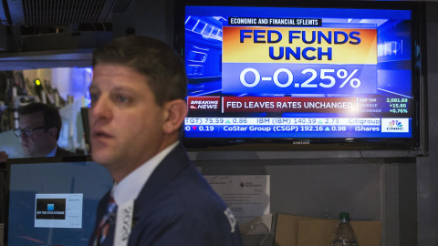 Un operador de la bolsa de Wall Street junto a un monitor que muestra la noticia de la decisión de la Reserva Federal de no tocar todavía los tipos de interés en EEUU. REUTERS/Lucas Jackson