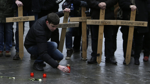 Un hombre coloca en el suelo una vela, junto a las cruces que recuerdan a los muertos en la plaza de Maida, en Kiev, en las revueltas contra el el régimen de Víctor Yanukovich. REUTERS/David W Cerny