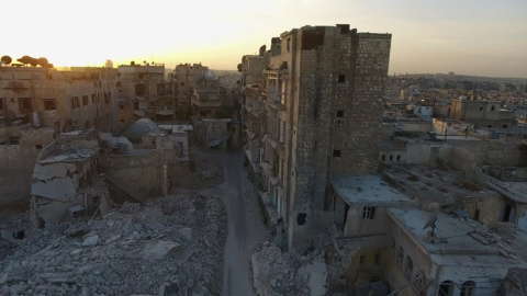 Imagen de archivo de dos personas pasando por una calle de Alepo destrozada por los  bombardeos. REUTERS