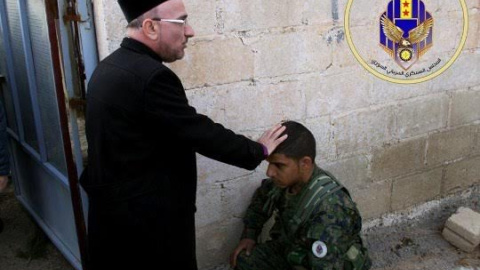 Sacerdote bendice a un miliciano del Consejo Militar Siriaco de Siria.