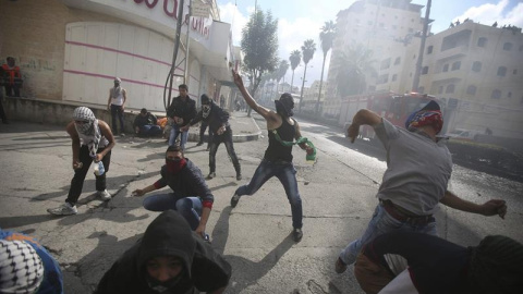 Manifestantes palestinos lanzan piedras contra soldados israelíes durante enfrentamientos en la ciudad cisjordana de Hebrón. EFE/ABED AL HASHLAMOUN