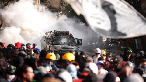 Manifestantes se enfrentan con las Fuerzas Especiales de Carabineros mientras una bandera con la cara del cantautor chileno Víctor Jara, asesinado durante la dictadura militar, ondea este viernes en los alrededores de la plaza Italia de San