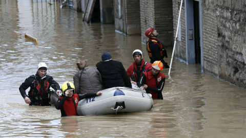 Miembros de la Cruz Roja y Bomberos evacuan a dos personas mayores de su vivienda que se encontraba completamente rodeada de agua en las calles del Casco Viejo de Tudela. /Jesús Diges (EFE)