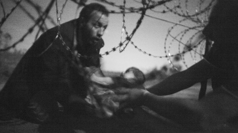 Un bebé es entregado a través de una alambrada de púas a un refugiado sirio que ha conseguido cruzar la frontera de Serbia a Hungría, cerca de Röszke, el 28 de agosto. - WARREN RICHARDSON / Primer premio Fotografías Individuales WPF 2015