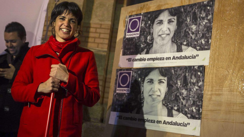 La candidata a la Presidencia de la Junta por Podemos, Teresa Rodríguez, ayuda a pegar los carteles electorales durante el acto de inicio de la campaña electoral andaluza celebrado anoche en la plaza Fragela, en Cádiz./ EFE