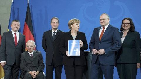 La canciller alemana Angela Merkel con el informe anual del Consejo Asesor de Economistas del Gobierno alemán, con su presidente Christoph Schmid a su izquierda. REUTERS/Stefanie Loos