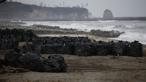 Grandes bolsas de plástico que contienen restos de tierra, hojas y desechos contaminados, son depositados en las costa devastada por el tsunami en Tomioka, provincia de Fukushima./ REUTERS-Toru Hanai