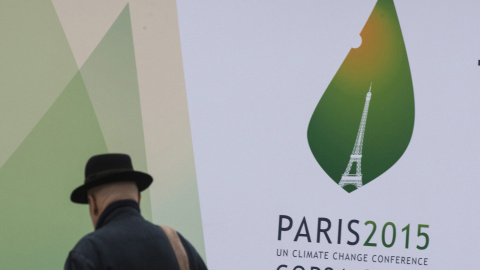 Un hombre pasa por delante del cartel de la cumbre del clima en París. REUTERS