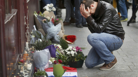 Un hombre se arrodilla en las afueras del restaurante Le Carillon  de París, uno de los objetivos de los ataques de los terroristas. - REUTERS