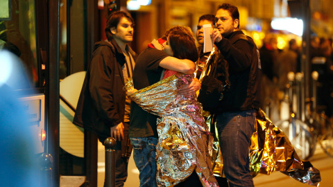 Supervivientes se abrazan antes de ser evacuados en autobús, cerca de la sala de conciertos Bataclan en París, donde los terroristas han matado a más de 100 rehenes.-  AFP PHOTO / FRANCOIS GUILLOT