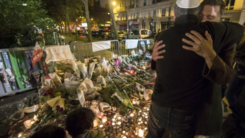 Dos hombres se abrazan junto a la sala Bataclan durante la vigilia en honor de las víctimas de los atentados. - EFE